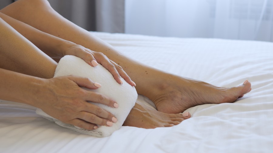 Osoba na zdjęciu stosuje zimny okład na stopy, co może sugerować, że doświadcza obrzęku stóp. Spuchnięte stopy mogą być spowodowane różnymi czynnikami, takimi jak długotrwałe stanie, niewydolność żylna lub problemy z krążeniem. Zimne kompresy mogą pomóc zmniejszyć obrzęk i przynieść ulgę.